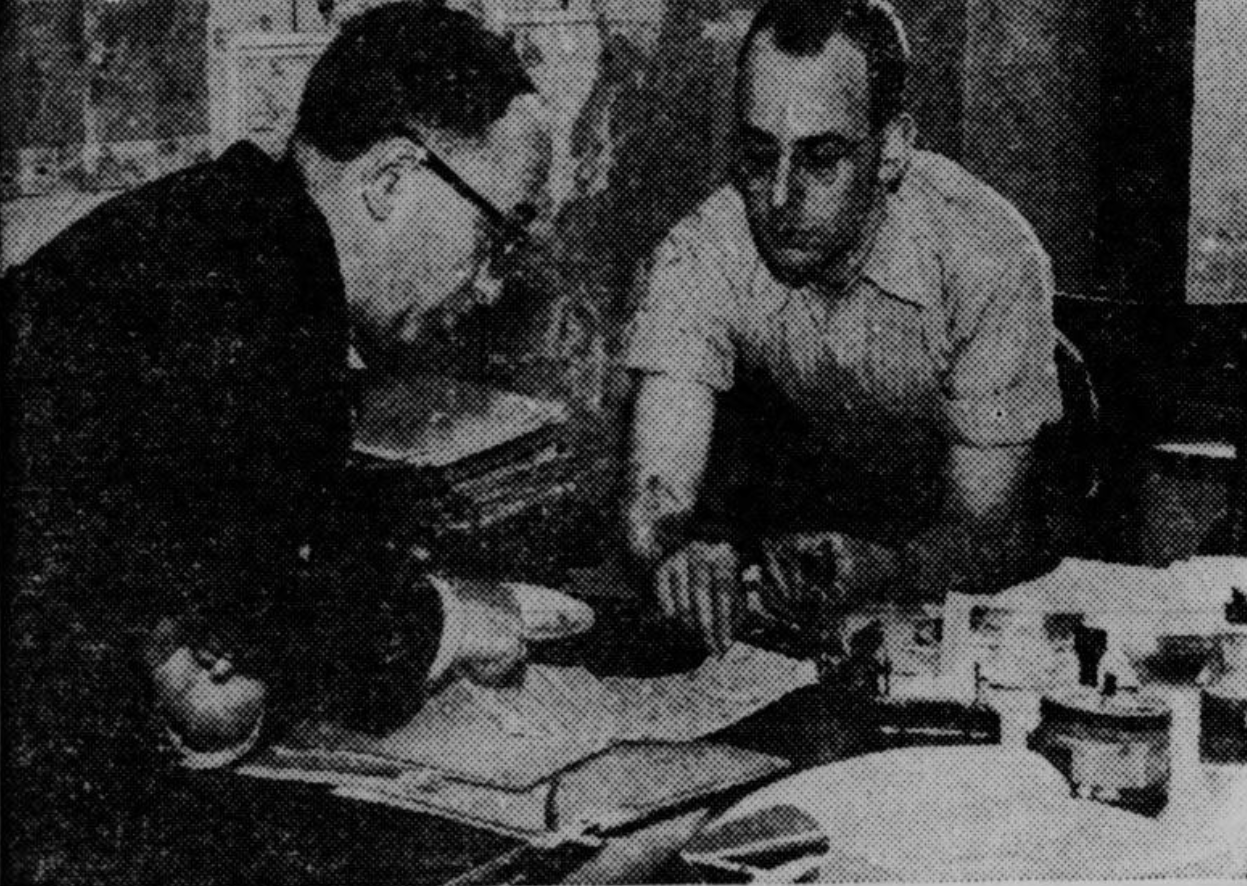 Kurt Hellmer with Richard Dyke at a desk covered in papers
